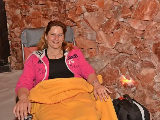 Entspannte Frau in der Bad Salzuflen Salzgrotte, umgeben von rosa Salzsteinen.