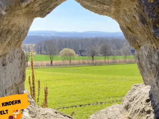 Blick durch eine Felsöffnung auf grüne Felder und Bäume. Perfekt für Ausflugsziele OWL mit Kindern, um die Natur zu entdecken.