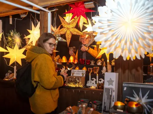 Besucherin auf einem velen Waldweihnachtsmarkt, umgeben von leuchtenden Sternen und weihnachtlicher Deko.