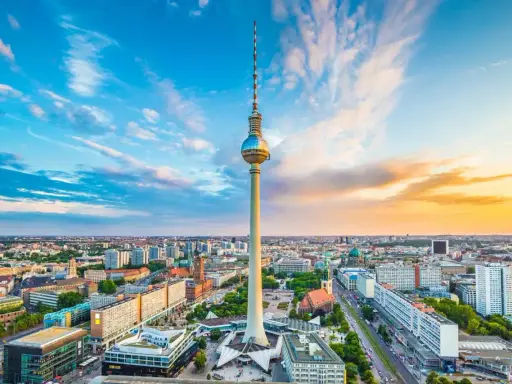 Der Berliner Fernsehturm mit seiner Aussichtsplattform ragt über die Stadt. Ein dramatischer Himmel mit Wolken und Abendsonne umrahmt das Wahrzeichen.