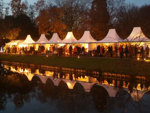 Festliche Zelte am havixbeck weihnachtsmarkt spiegeln sich im Wasser. Besucher bummeln durch die beleuchteten Stände.