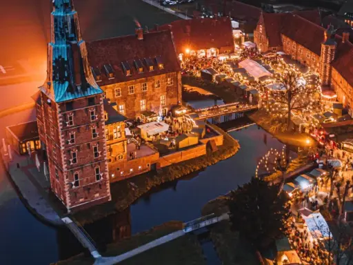 Magischer adventsmarkt raesfeld mit beleuchtetem Wasserschloss und vielen Buden.