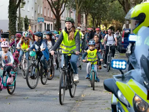 Kinder und Erwachsene radeln bei der Kidical Mass Dortmund. Viele tragen Warnwesten und Helme.