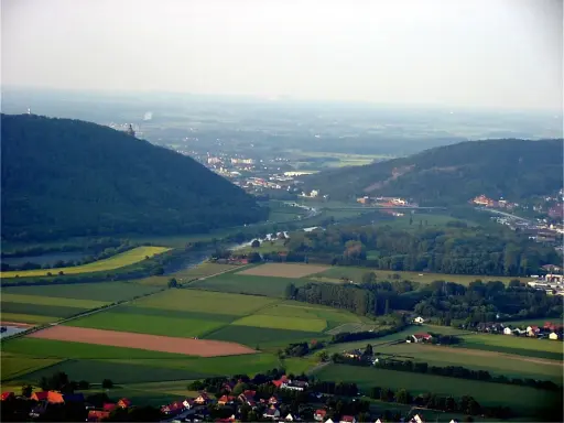 Blick über das Wesertal bei Porta Westfalica mit bewaldeten Hügeln, Feldern und der Stadt.