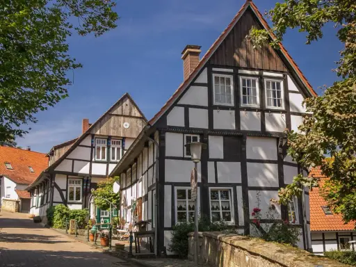 Fachwerkhäuser säumen eine Gasse in der Tecklenburg Altstadt. Ein Baum wirft Schatten auf die Straße.