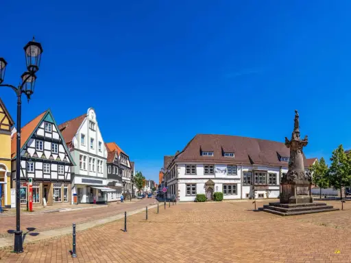 Blick über den Marktplatz der horn-bad meinberg altstadt mit Fachwerkhäusern, einem Denkmal und blauem Himmel.