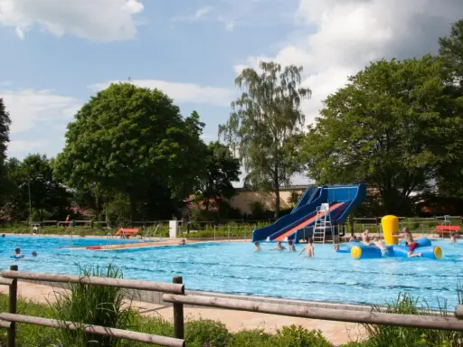 Ein sonniger Tag im Freibad Lahde. Kinder planschen im Wasser, rutschen und spielen auf einem aufblasbaren Spielzeug.