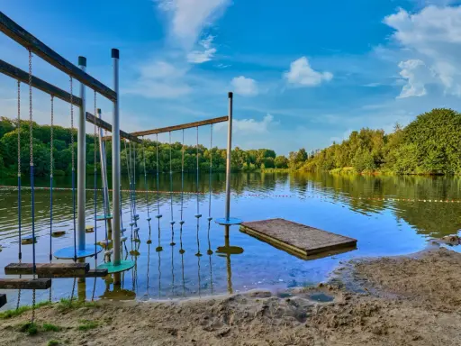 Borken am See: Ein Hindernisparcours im Wasser lädt zum Spielen ein. Der Sandstrand und die grüne Uferkulisse versprechen einen schönen Sommertag.