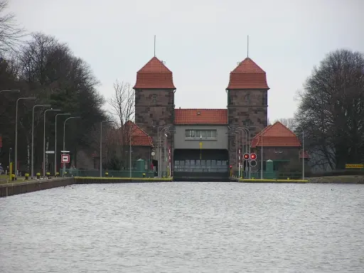 Die Schachtschleuse Minden mit ihren markanten Türmen und roten Ziegeldächern ragt über das ruhige Wasser.