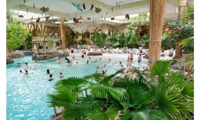 Familien genießen das tropische Ambiente und das Wasser in der **Therme Sauerland**. Palmen und eine Strandbar schaffen Urlaubsfeeling.
