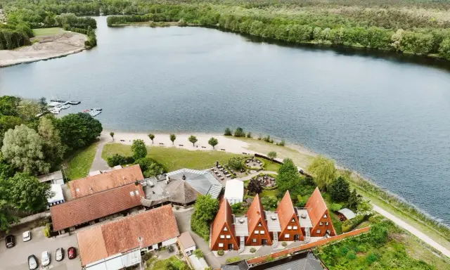 Idyllischer Seeuferbereich mit Sandstrand, Booten und Häusern. Ein perfekter Ort für einen entspannten Seeurlaub in Gronau.