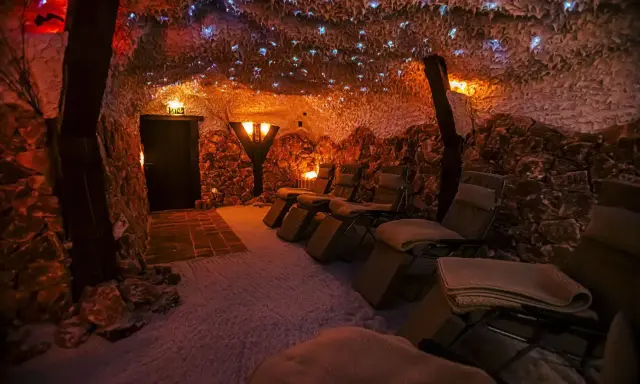 Entspannende Liegestühle in einer **Salzgrotte Paderborn**. Die Wände sind mit Salzsteinen verkleidet, die Decke funkelt mit kleinen Lichtern.