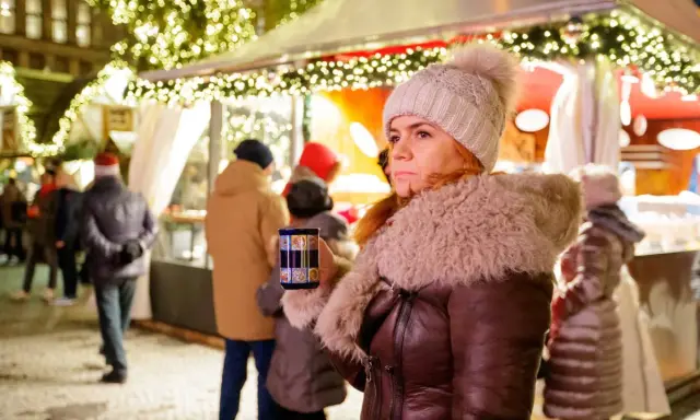 Frau mit Becher auf dem **Weihnachtsmarkt Nottuln**, umgeben von Lichtern und Menschen.