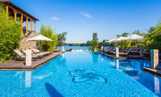 Entspannung pur im Solebad NRW: Ein luxuriöser Pool mit Blick auf den See, umgeben von Bambus und Liegestühlen.