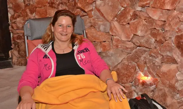 Entspannte Frau in der Bad Salzuflen Salzgrotte, umgeben von rosa Salzsteinen.