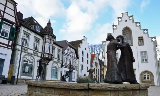 Skulpturen auf dem Markt Brakel vor Fachwerkhäusern und einem weißen Giebelhaus.