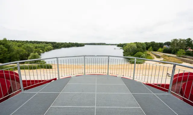 Blick vom Aussichtsturm auf den Offlumer See mit Sandstrand und grünen Ufern.