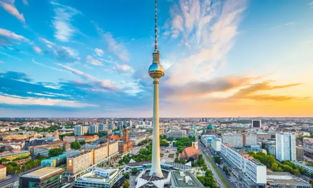 Der Berliner Fernsehturm mit seiner Aussichtsplattform ragt über die Stadt. Ein dramatischer Himmel mit Wolken und Abendsonne umrahmt das Wahrzeichen.