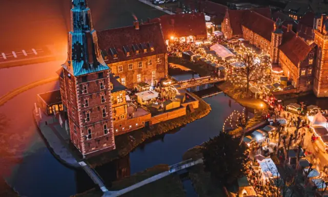 Magischer adventsmarkt raesfeld mit beleuchtetem Wasserschloss und vielen Buden.