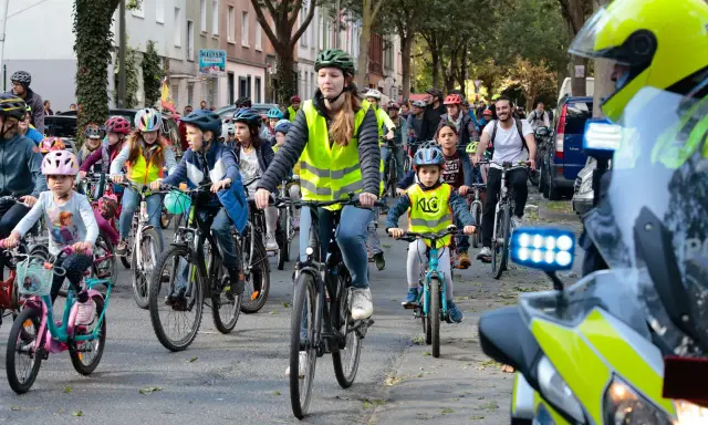 Kinder und Erwachsene radeln bei der Kidical Mass Dortmund. Viele tragen Warnwesten und Helme.