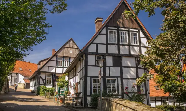 Fachwerkhäuser säumen eine Gasse in der Tecklenburg Altstadt. Ein Baum wirft Schatten auf die Straße.