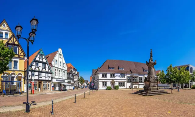 Blick über den Marktplatz der horn-bad meinberg altstadt mit Fachwerkhäusern, einem Denkmal und blauem Himmel.