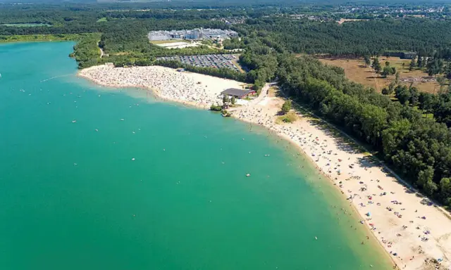 Sonniger Tag am **Silbersee Haltern am See**. Tausende Besucher genießen das türkisfarbene Wasser und den breiten Sandstrand, umgeben von grünen Wäldern.