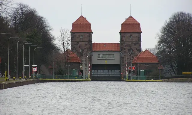 Die Schachtschleuse Minden mit ihren markanten Türmen und roten Ziegeldächern ragt über das ruhige Wasser.