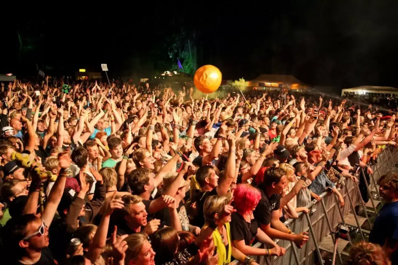 Eine riesige Menge jubelt beim Stemweder Open Air. Eine orangefarbene Kugel schwebt &uuml;ber den K&ouml;pfen der begeisterten Fans.