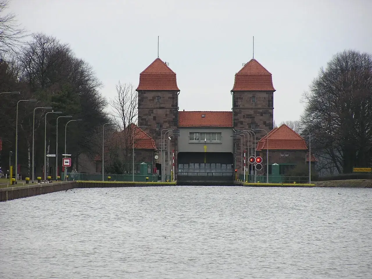 Die Schachtschleuse Minden mit ihren markanten T&uuml;rmen und roten Ziegeld&auml;chern &uuml;ber dem ruhigen Wasser.