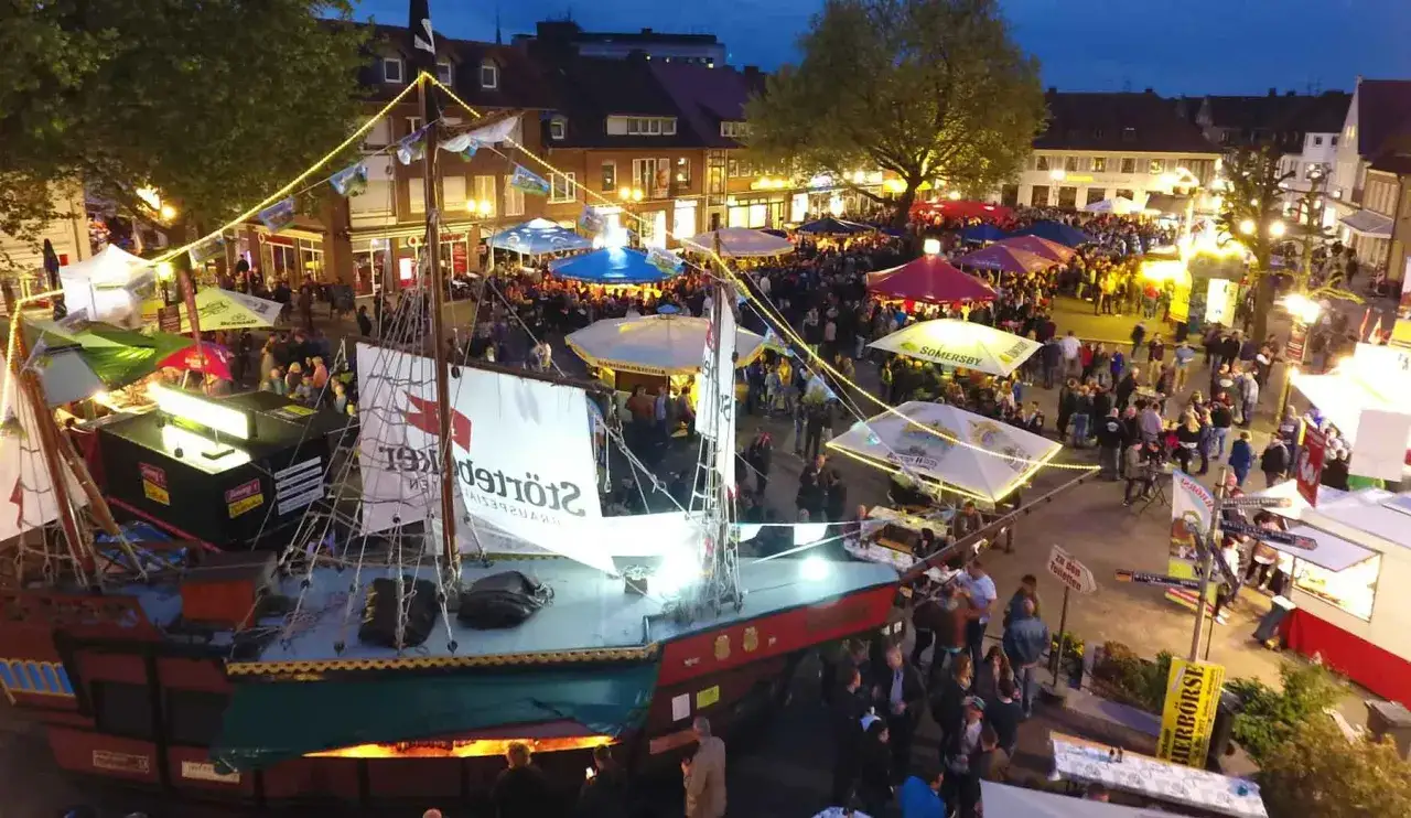 Festliche Veranstaltungen im Kreis Borken: Ein Piratenschiff-Imbisswagen und bunte St&auml;nde beleben den Platz bei Nacht.