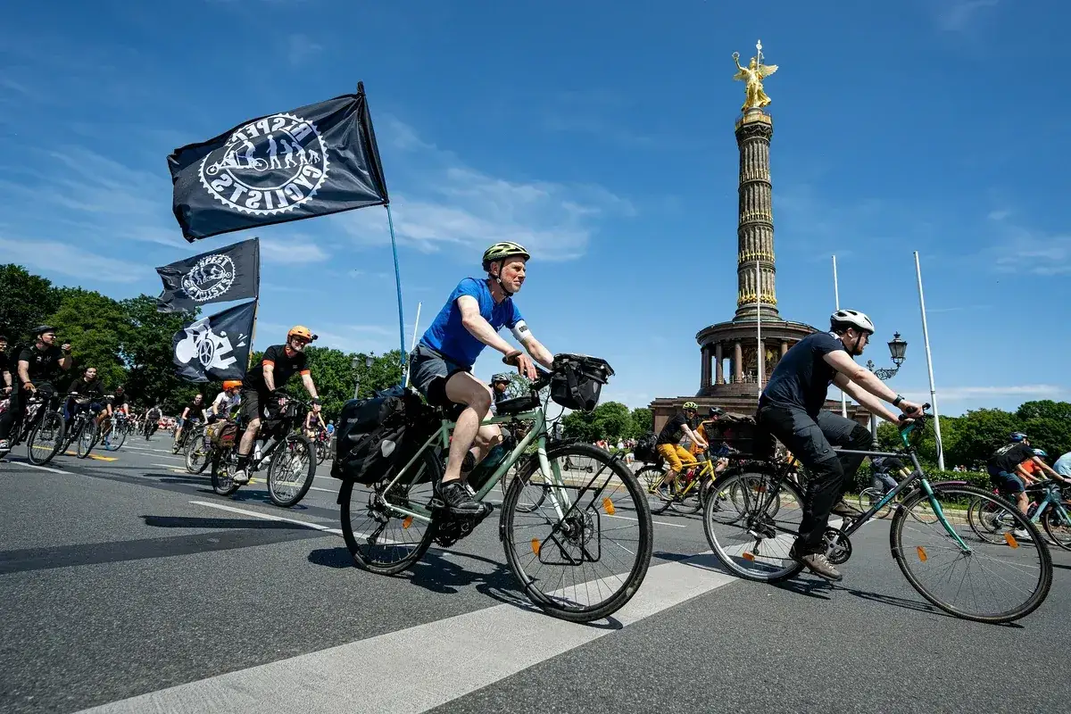 Fahrradfahrer bei der ADFC Sternfahrt in Berlin, mit Fahnen und der Siegessäule im Hintergrund.