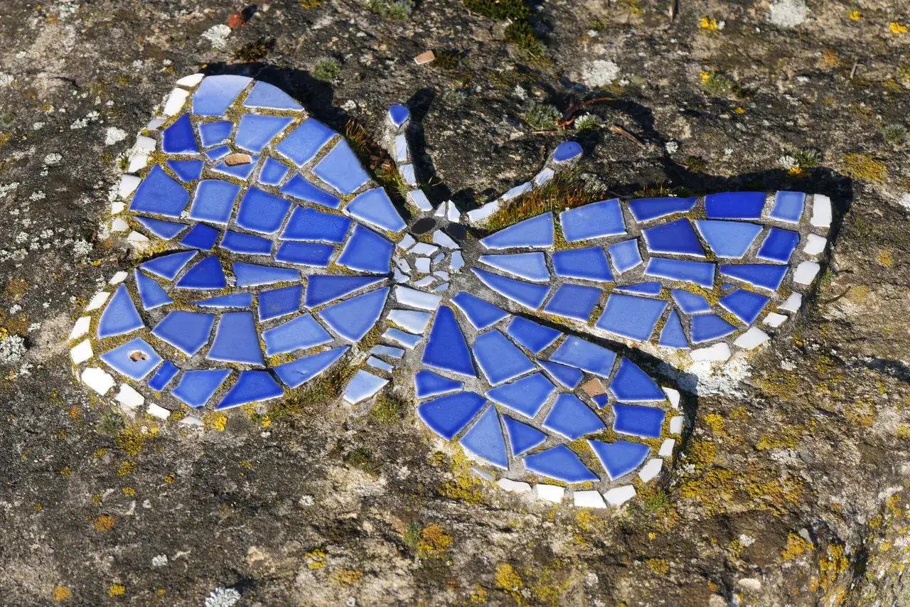 Mosaik-Schmetterling aus blauen und wei&szlig;en Kacheln auf einem Stein, Teil des Schmetterlingspfad Willebadessen.