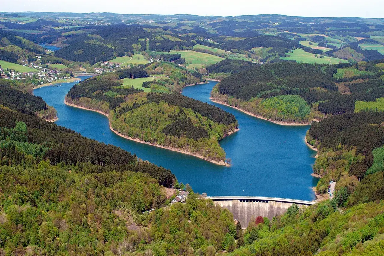 Idyllische Landschaft in NRW: Ein See schlängelt sich durch bewaldete Hügel. Perfekt zum spazieren gehen und die Natur genießen.