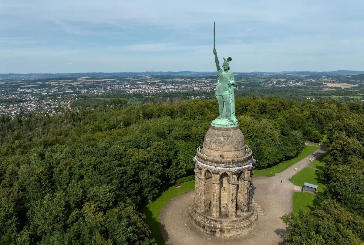 Das Hermannsdenkmal thront &uuml;ber einem gr&uuml;nen Wald. Besucher genie&szlig;en das Wandern und die Aussicht auf die Stadt.