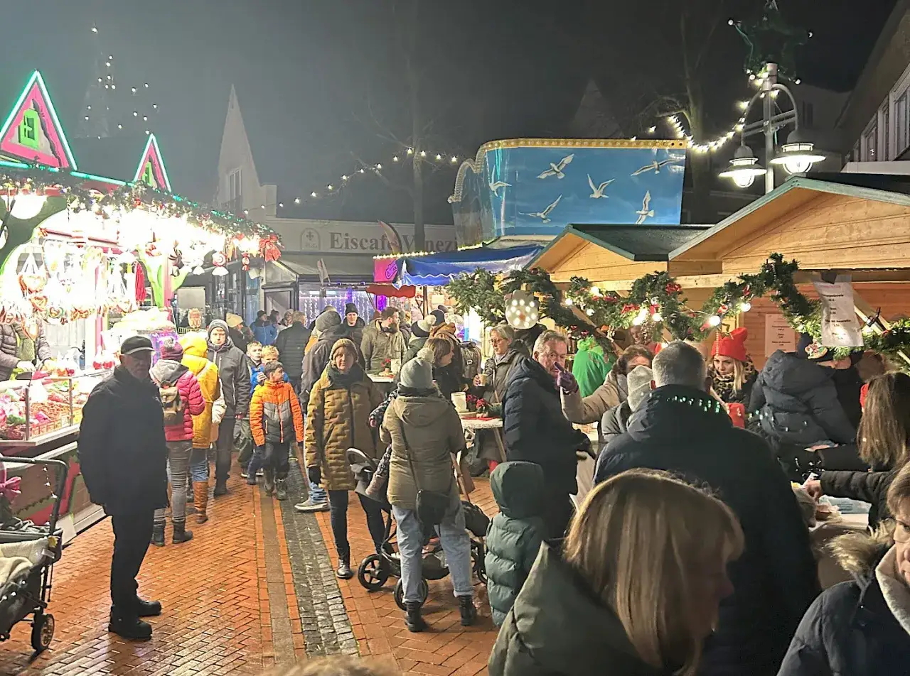 Menschenmassen auf einem Weihnachtsmarkt im Kreis Steinfurt. Stände mit Lichtern und Dekorationen, festliche Atmosphäre.