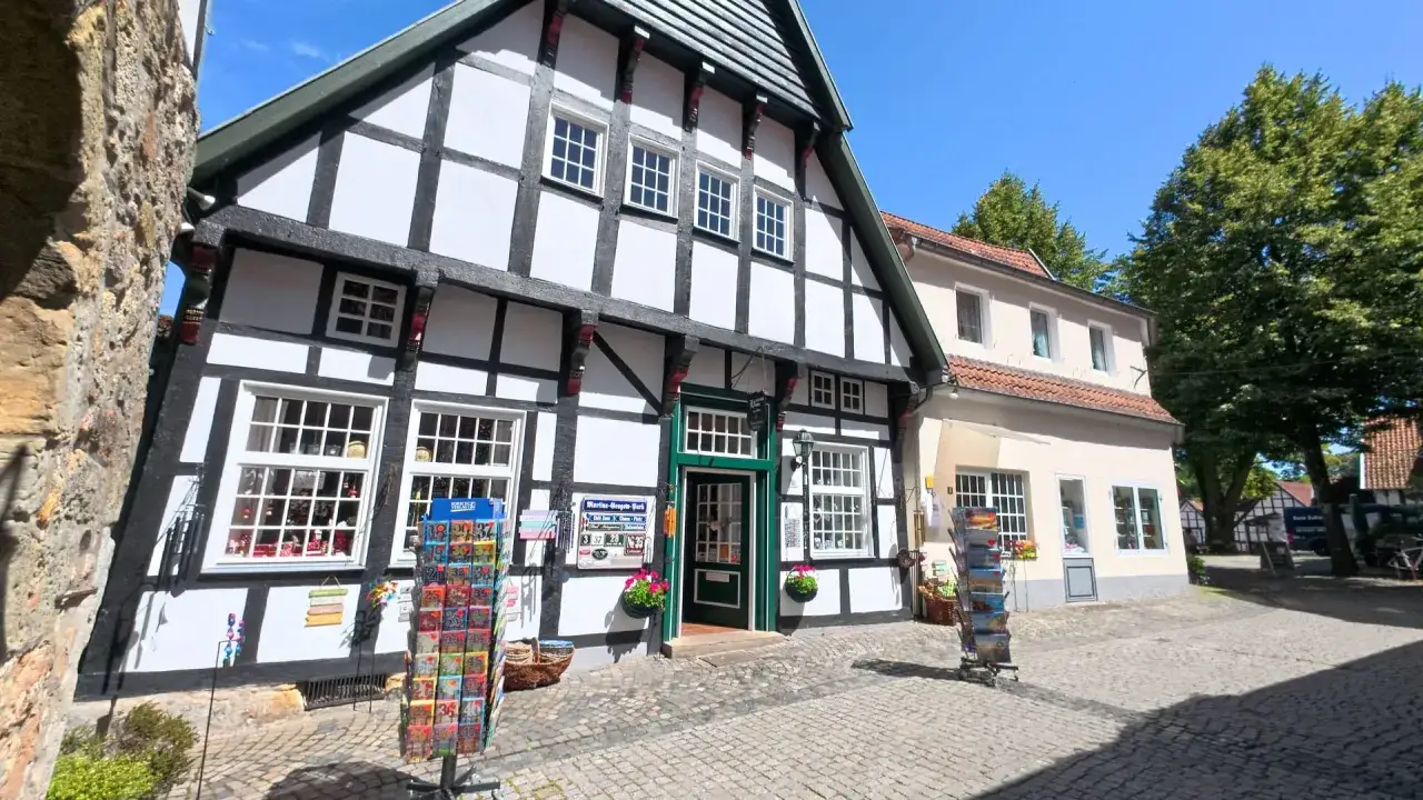 Fachwerkhaus in der Tecklenburger Altstadt mit Geschäften und Postkartenständern.