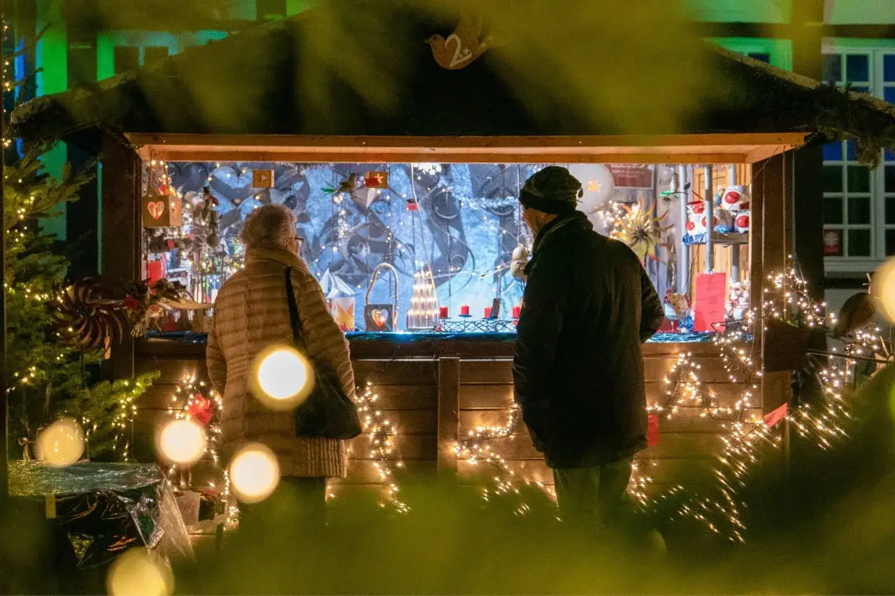 Ein Paar betrachtet die festliche Dekoration auf dem weihnachtsmarkt werne. Lichterketten und Adventsschmuck erhellen die Szene.