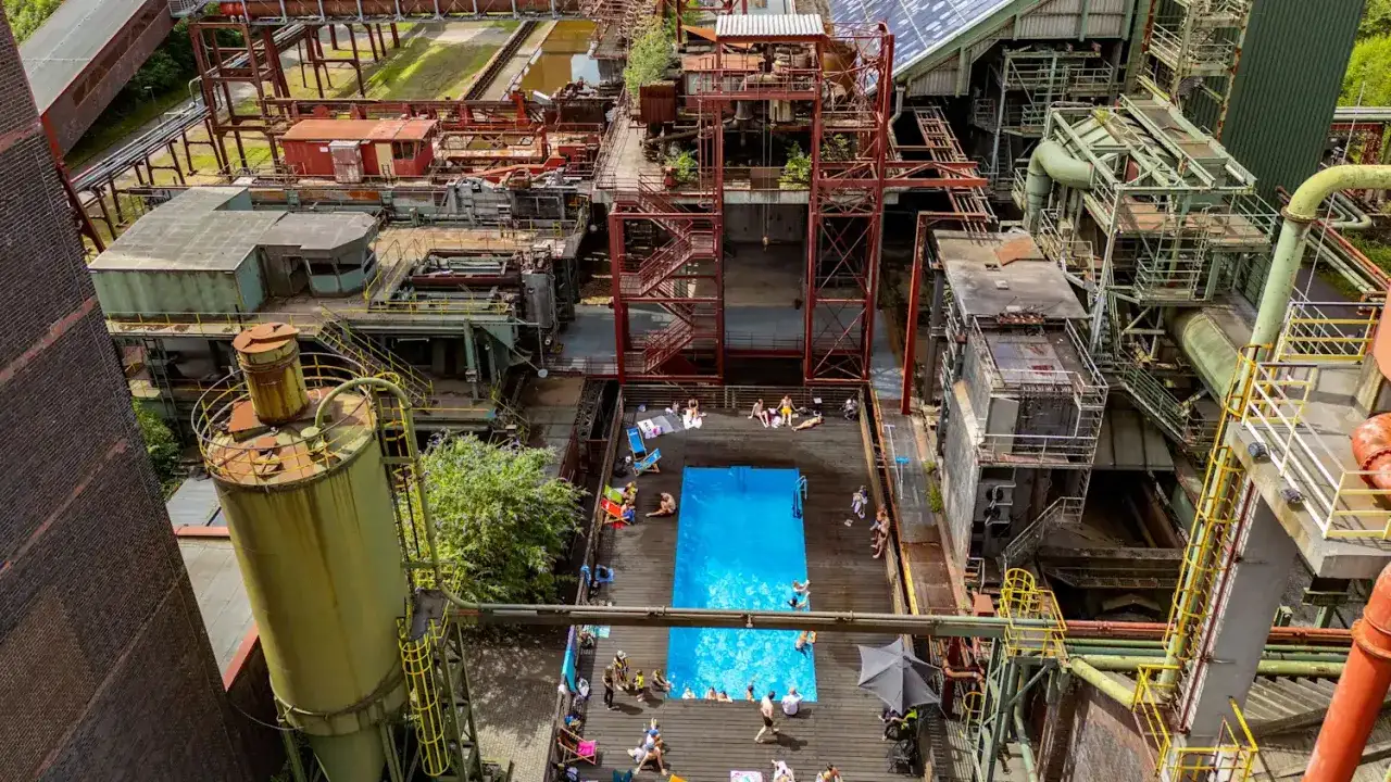 Ein Pool mit Badegästen inmitten einer stillgelegten Industrieanlage. Ein ungewöhnlicher Ort, der zeigt, wie sich das Leben in der Stadt wandelt.