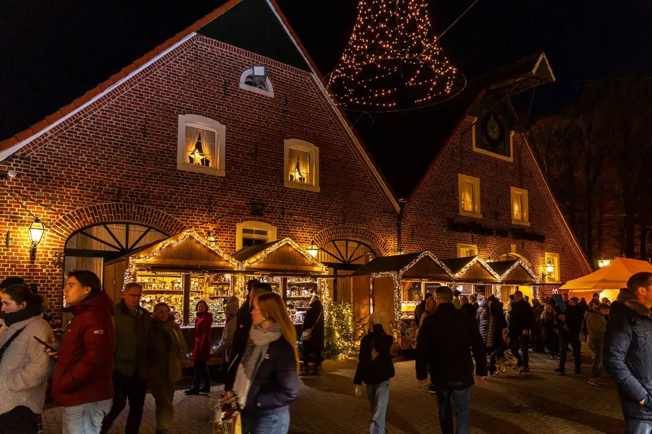 Besucher genie&szlig;en die festliche Atmosph&auml;re bei Veranstaltungen in Velen. Weihnachtliche Buden und Lichterketten schm&uuml;cken die Ziegelgeb&auml;ude.