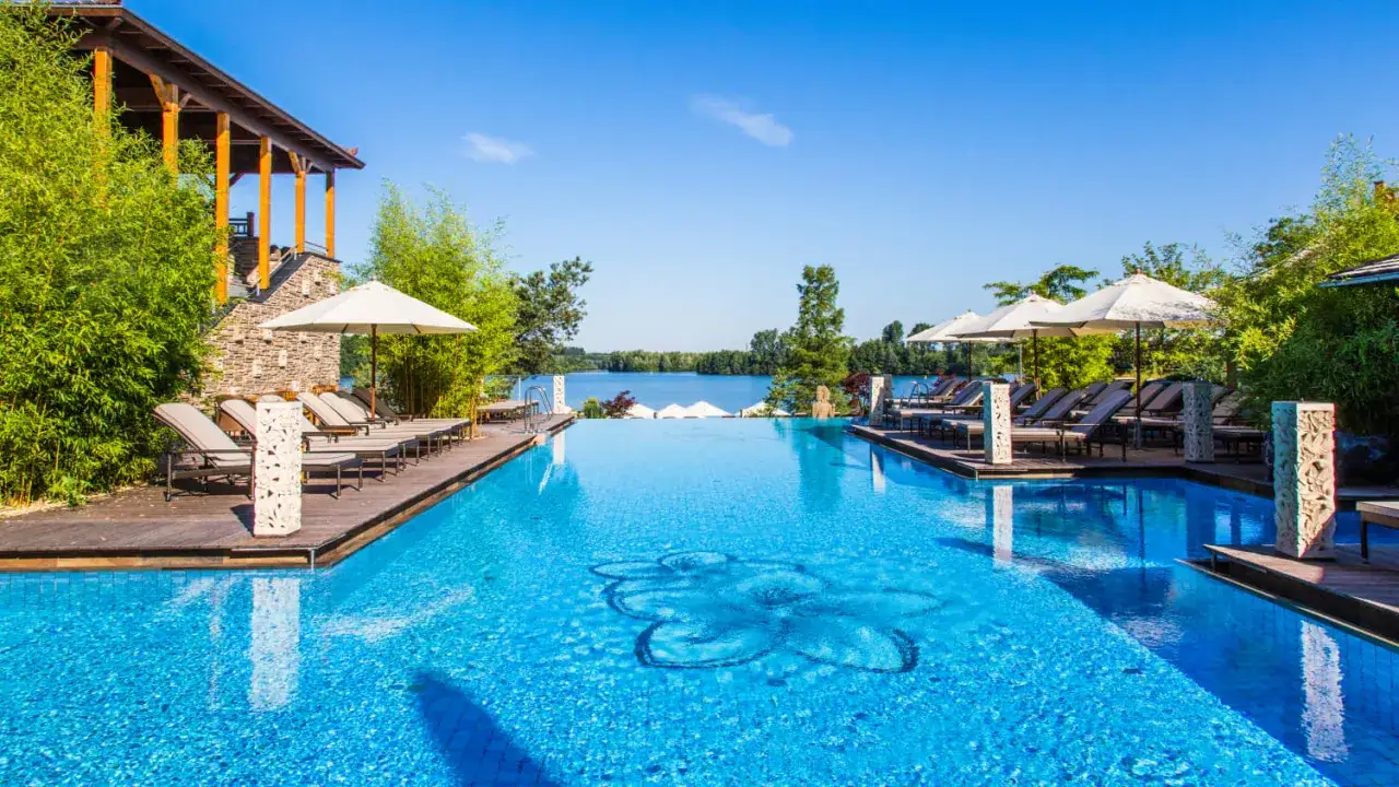 Entspannung pur im Solebad NRW: Ein luxuriöser Pool mit Blick auf den See, umgeben von Bambus und Liegestühlen.
