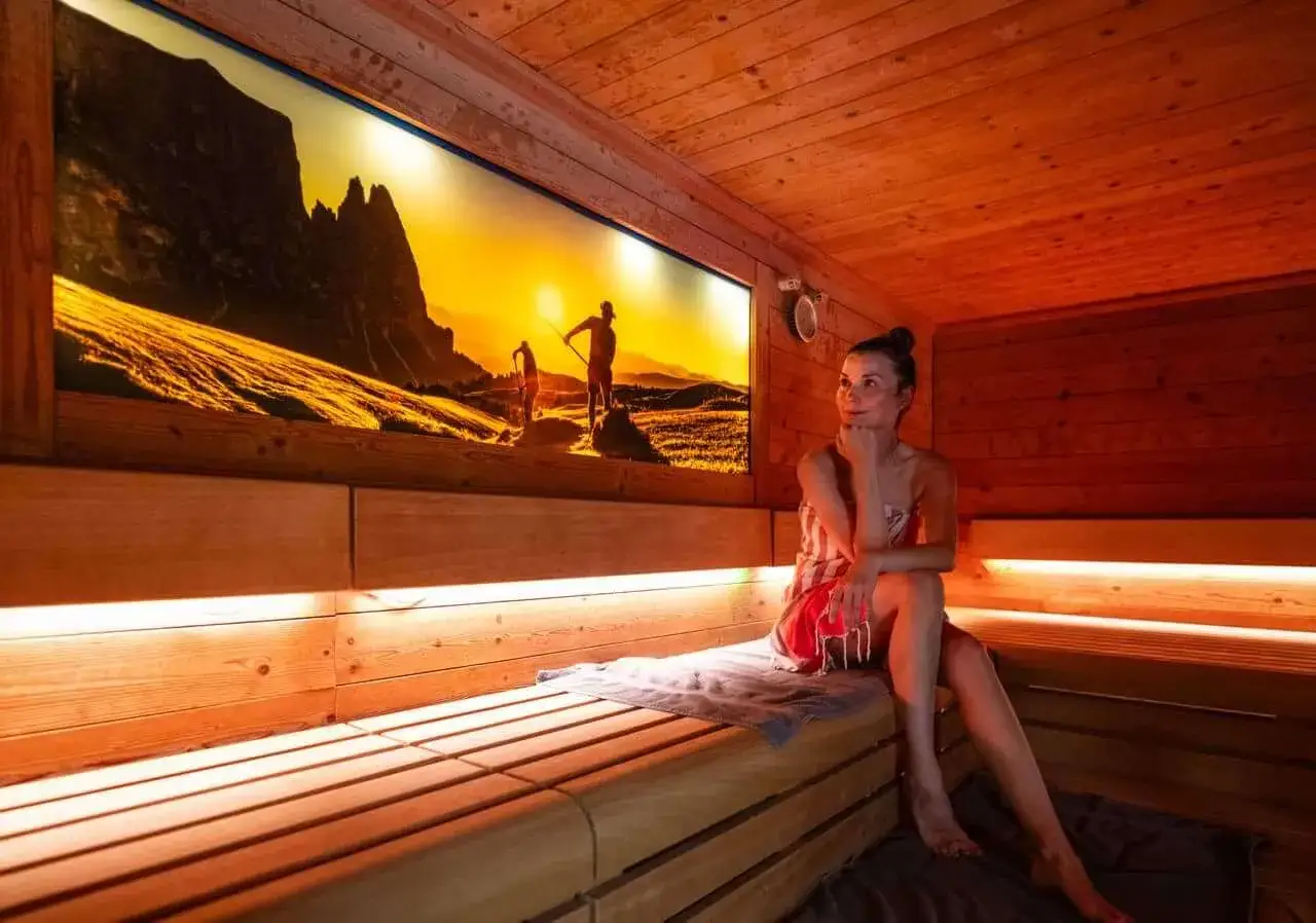 Entspannung in der Therme Bad Driburg: Eine Frau genie&szlig;t die W&auml;rme in der Sauna, w&auml;hrend ein Bergpanorama die Wand ziert.