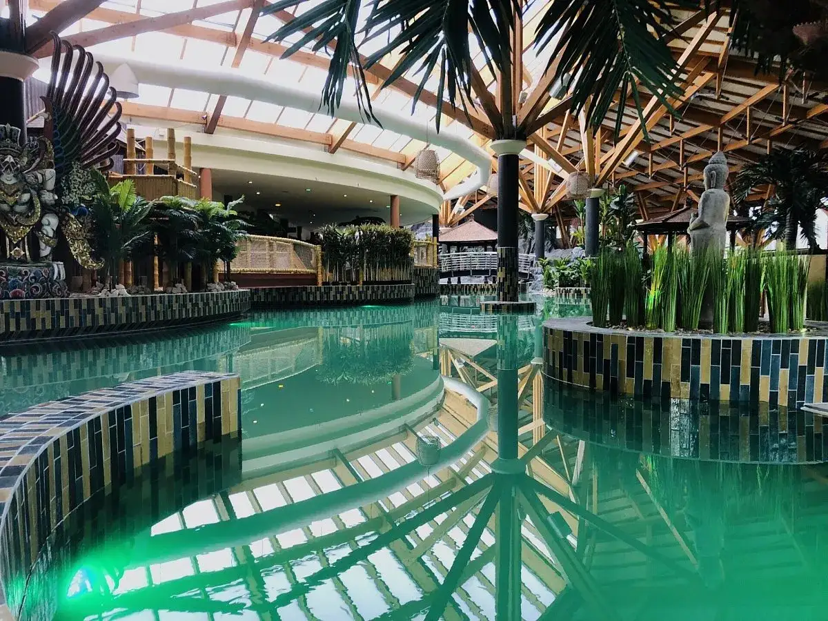 Entspannende Bali Therme mit tropischer Deko, Buddha-Statue und einem großen Pool.