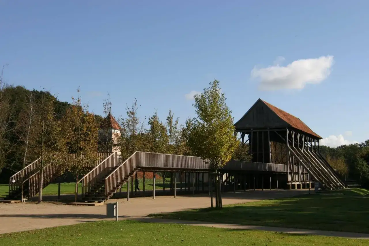 Holzkonstruktion einer Gradierwand, die an eine Saline erinnert, mit Treppen und einem kleinen Turm im Hintergrund.