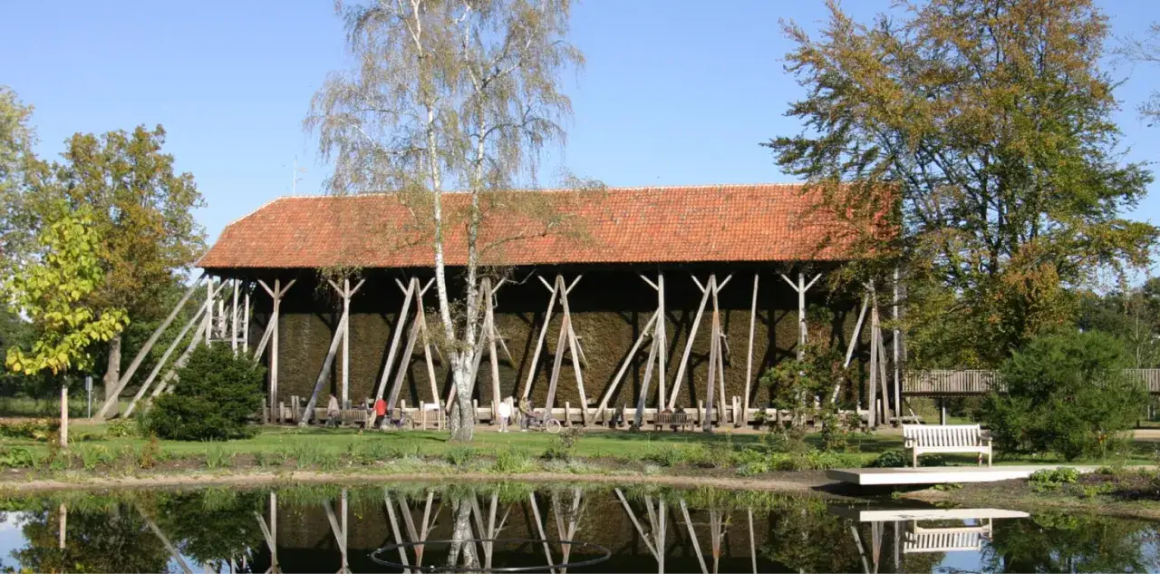 Gro&szlig;e Gradierwerke mit roten Ziegeld&auml;chern, umgeben von B&auml;umen und einem Teich. Hier wird die Luft mit wertvollem saline rheine angereichert.