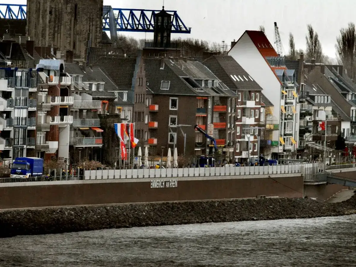 Bunte Häuserfront am Rhein in Emmerich Altstadt, mit Brücke und Kran im Hintergrund.
