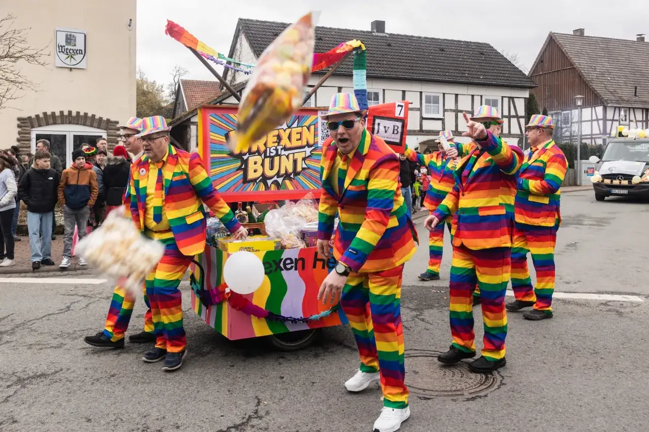 Bunte Kostüme und ein fröhlicher Wagen bei den Karnevalstagen. Die Narren werfen Süßigkeiten.