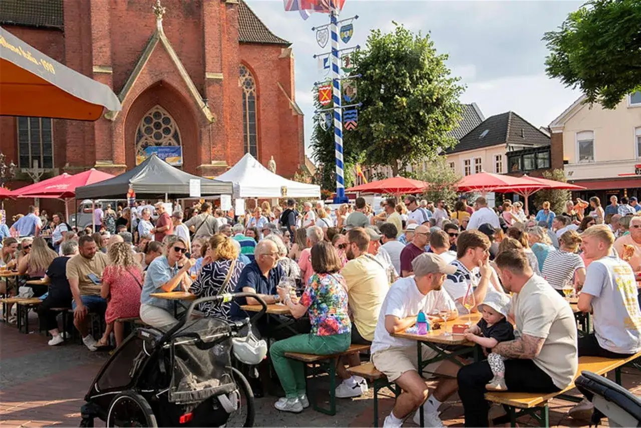 Buntes Treiben bei Haltern am See Veranstaltungen. Menschen sitzen an Tischen vor einer Kirche, genie&szlig;en das Fest.