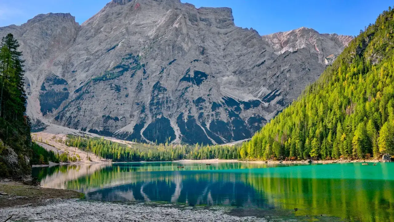 T&uuml;rkisblaue Bergsee mit Booten, umgeben von gr&uuml;nen W&auml;ldern und steilen Felsen. Ein versteckter Ort, wie ein Geheimtipp f&uuml;r Winterberg.