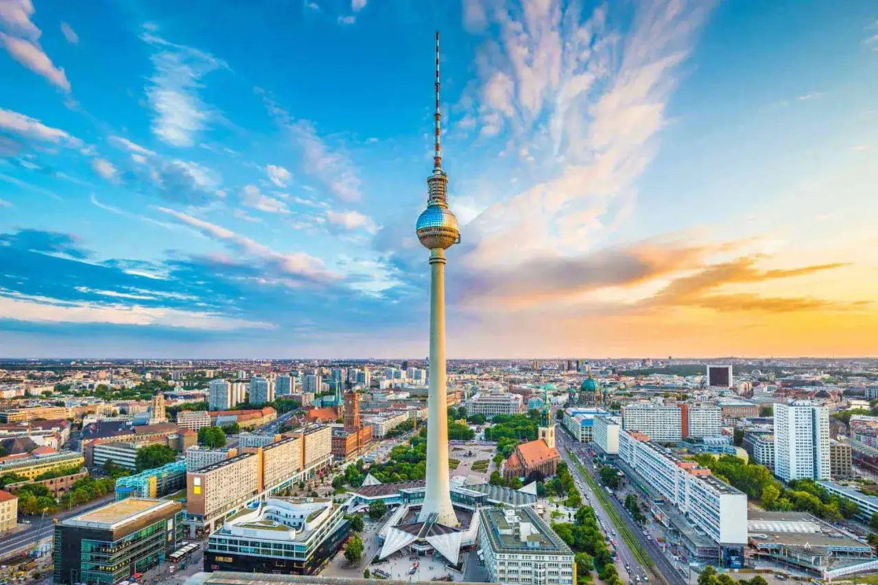 Der Berliner Fernsehturm mit seiner Aussichtsplattform ragt &uuml;ber die Stadt. Ein dramatischer Himmel mit Wolken und Abendsonne umrahmt das Wahrzeichen.